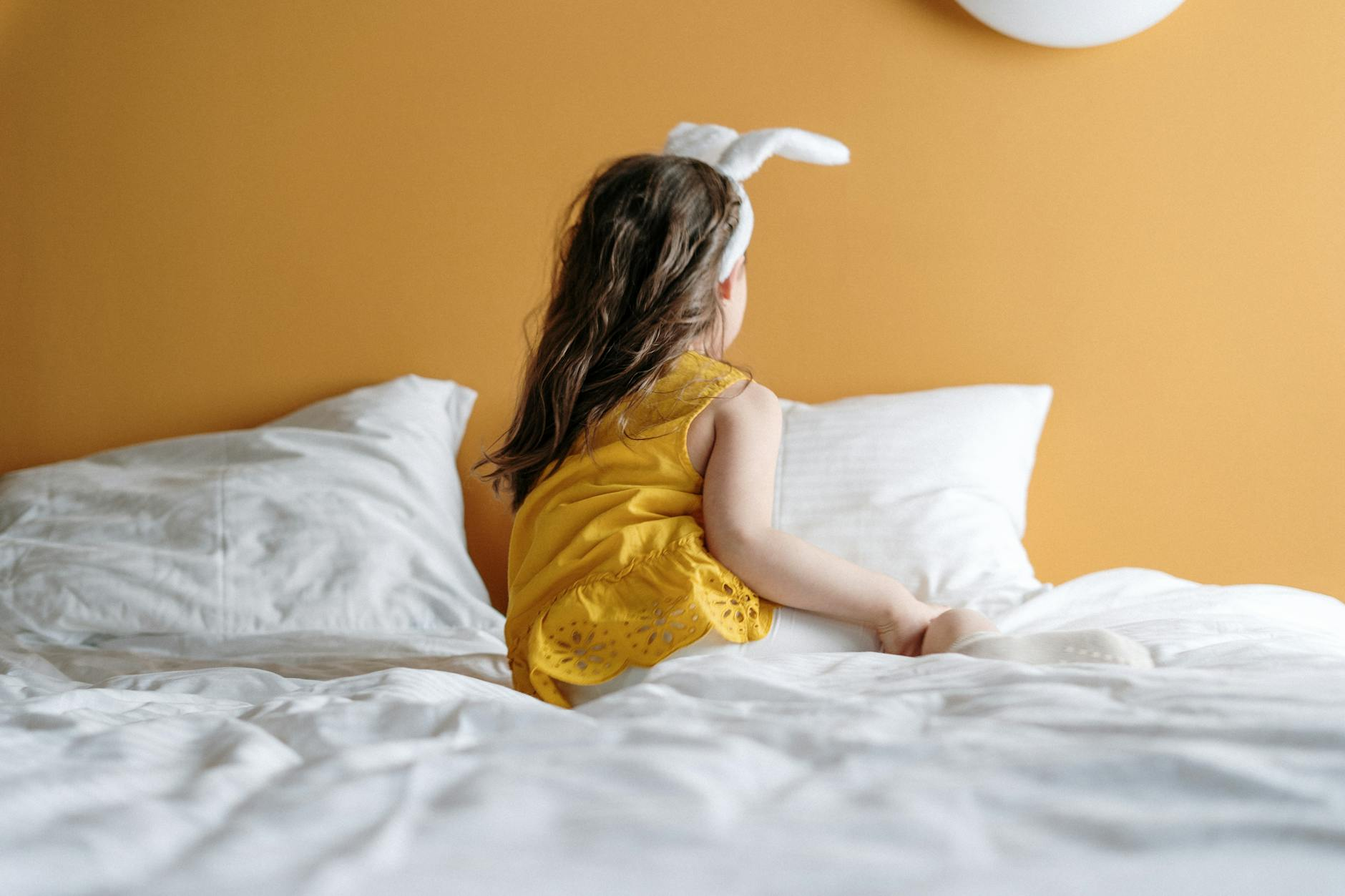 girl in yellow dress lying on bed