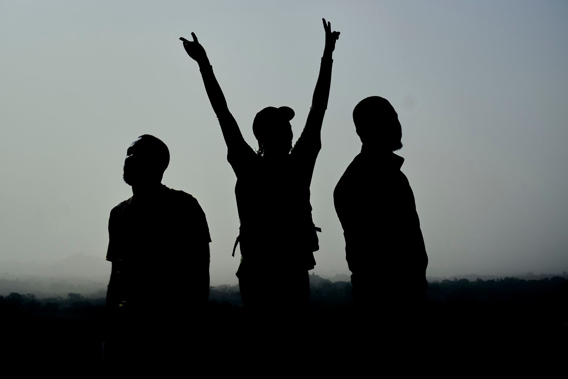 silhouettes of three people standing outside on a foggy day